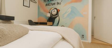A bedroom with a bed, a desk, and a wall mural.