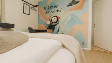 Un dormitorio con cama, escritorio y pared decorada con un mural colorido.
