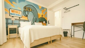 A bedroom with a bed, a nightstand, a desk, and a wall mural. - Stykkisholmur Inn (Stykkisholmur)