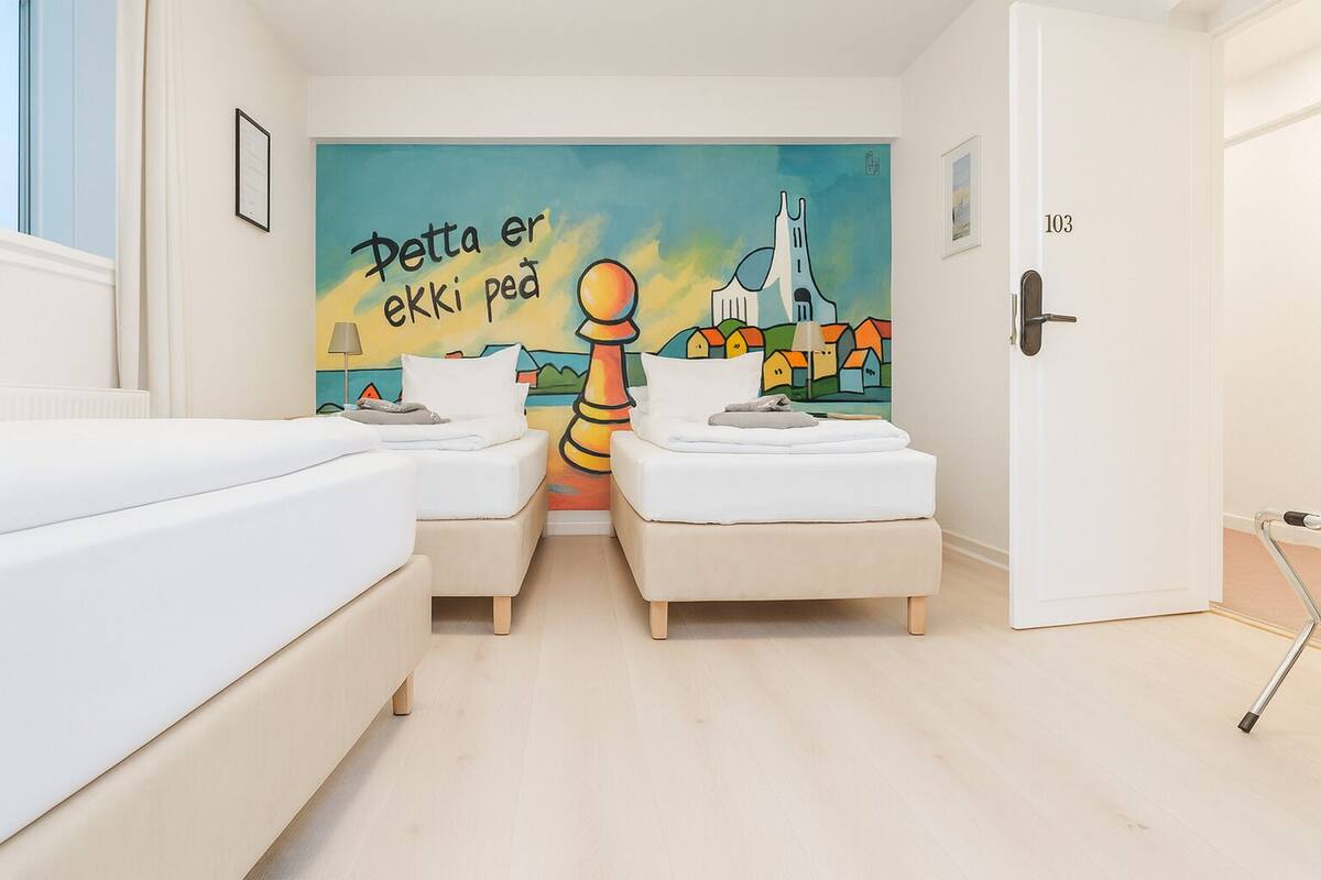 A room with two beds, a mural on the wall, and a door labeled "103".