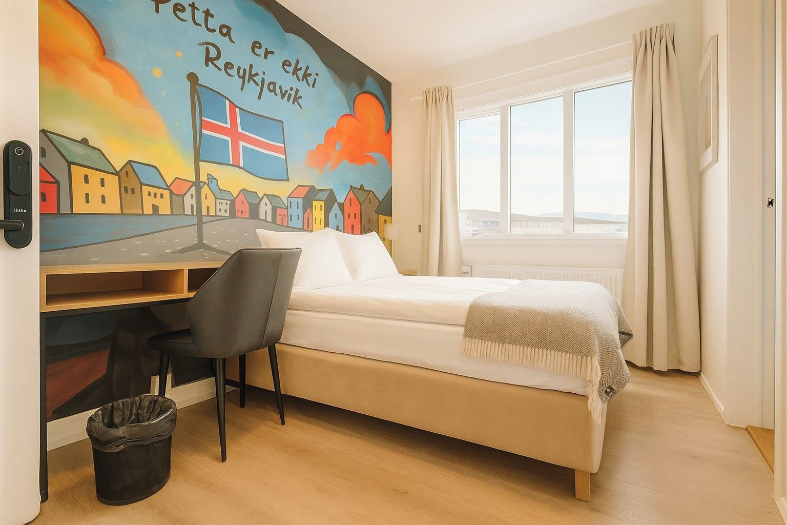 A bedroom with a bed, a desk, a chair, a window, and a wall mural.