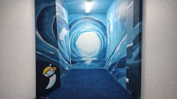 A hallway with a blue carpet and a mural of a tunnel with a penguin character.