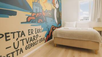 Un dormitorio con cama, un mural en la pared y una ventana.