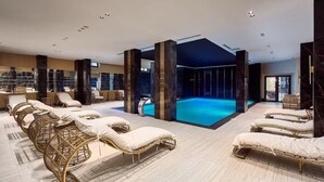 A modern spa area with lounge chairs, a pool, and a reception area. - Qoople Legends (Alanya)