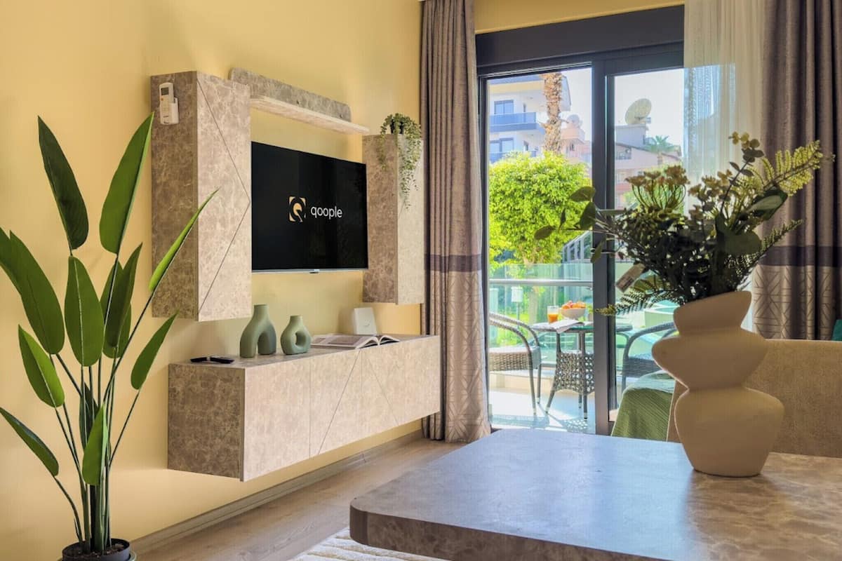 A modern living room with a flat-screen TV mounted on a marble wall, a coffee table, and a potted plant.