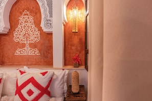 Een kamer met een decoratieve wand, een hanglamp en een tafeltje met een vaas.