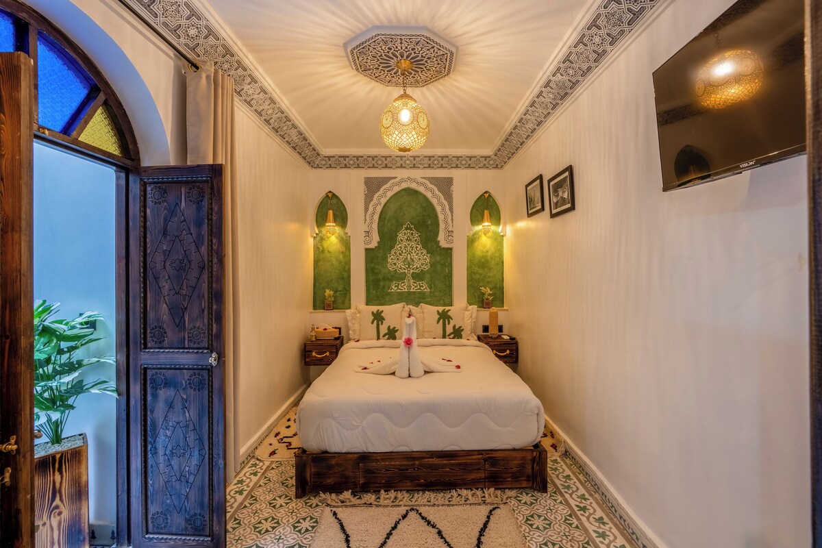 Une chambre dotée d’un grand lit, d’appliques murales décoratives, d’un lustre et d’un téléviseur fixé au mur.