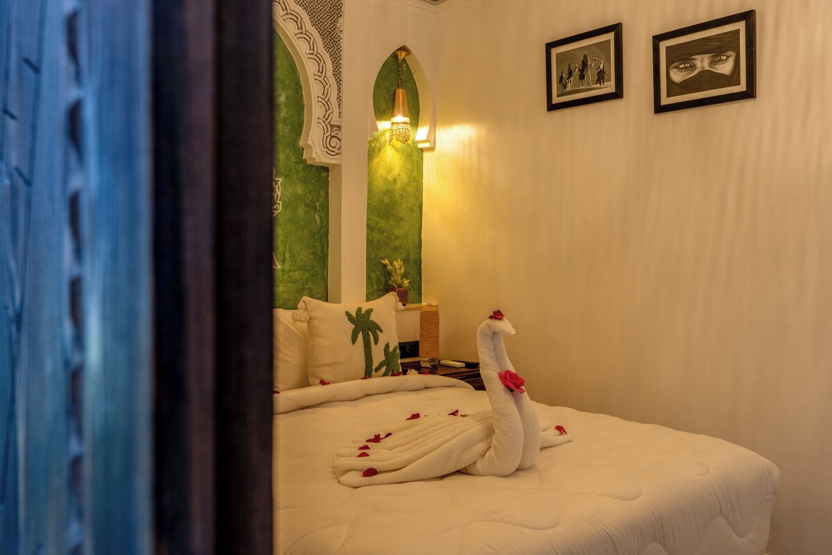 A hotel room with a bed, a decorative swan, and a green wall.