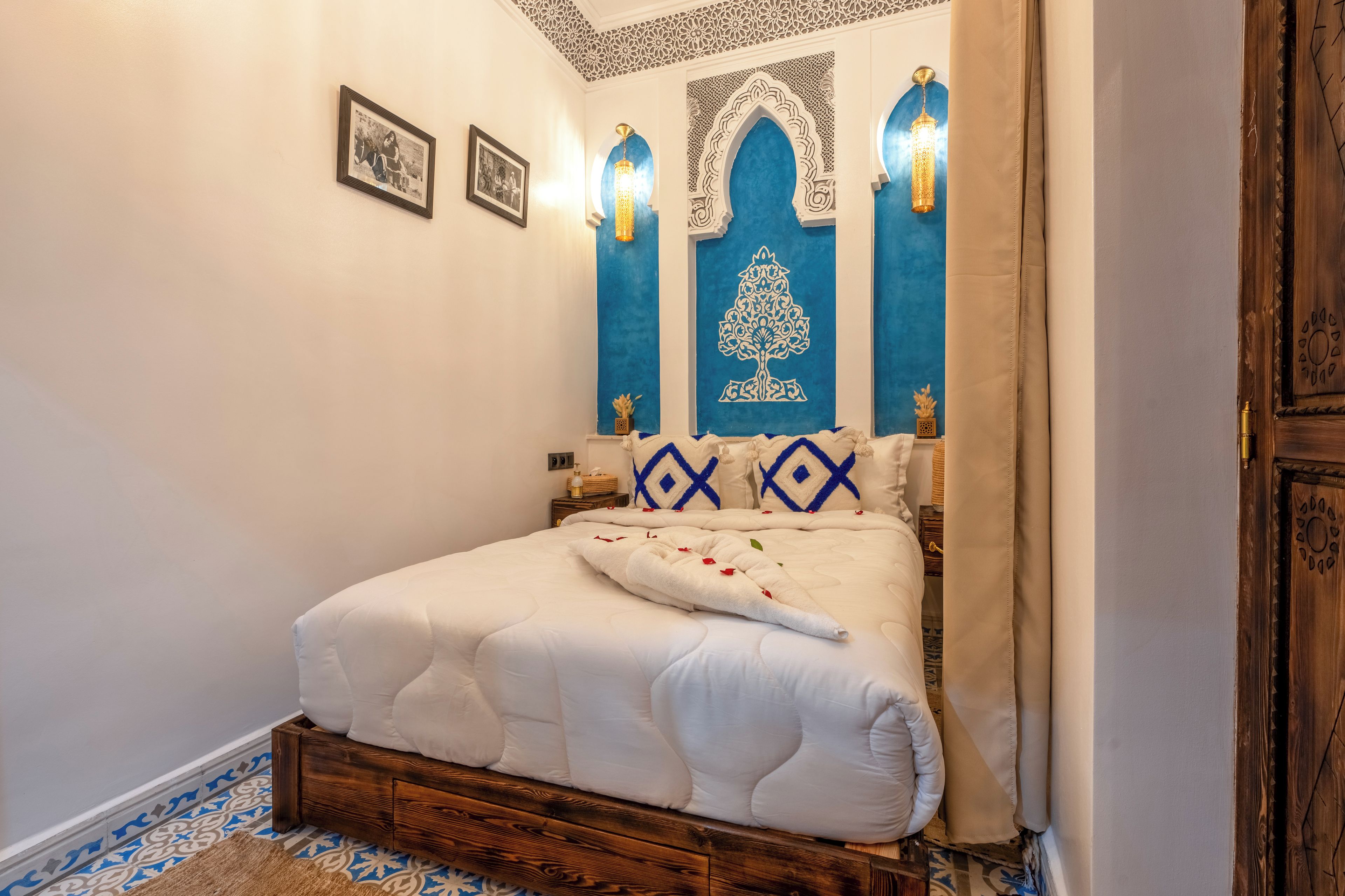 A bedroom with a wooden bed frame, a white bedspread, and blue and white patterned pillows.