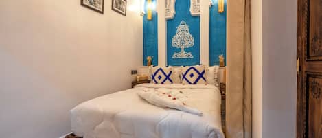 A bedroom with a wooden bed frame, a white bedspread, and blue and white patterned pillows.