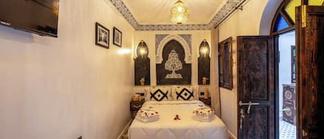 Une chambre dotée d’un grand lit, de panneaux muraux décoratifs, d’un téléviseur et d’un sol à motifs.