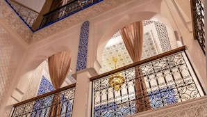 An interior with ornate arches, patterned tiles, and metal railings. - Riad La Perle Bleue (Marrakech)