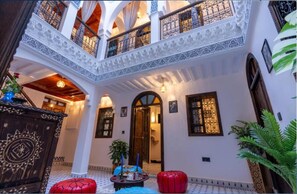 A traditional interior with a central courtyard, ornate wooden doors, and a balcony with intricate railings. - Riad La Perle Bleue (Marrakech)
