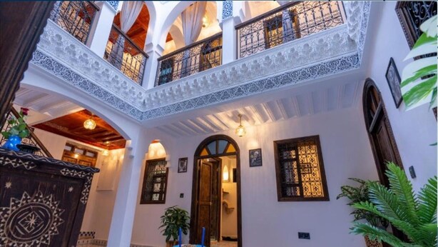 A traditional interior with a central courtyard, ornate wooden doors, and a balcony with intricate railings. - Riad La Perle Bleue (Marrakech)