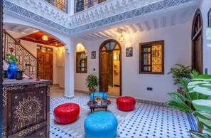 A multi-level interior with a tiled floor, wooden furniture, and decorative elements. - Riad La Perle Bleue (Marrakech)