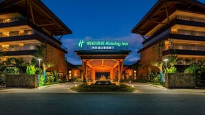 A hotel entrance with a prominent sign, a covered walkway, and a landscaped area with plants. - Holiday Inn Puer Jingmai (Pu'er)
