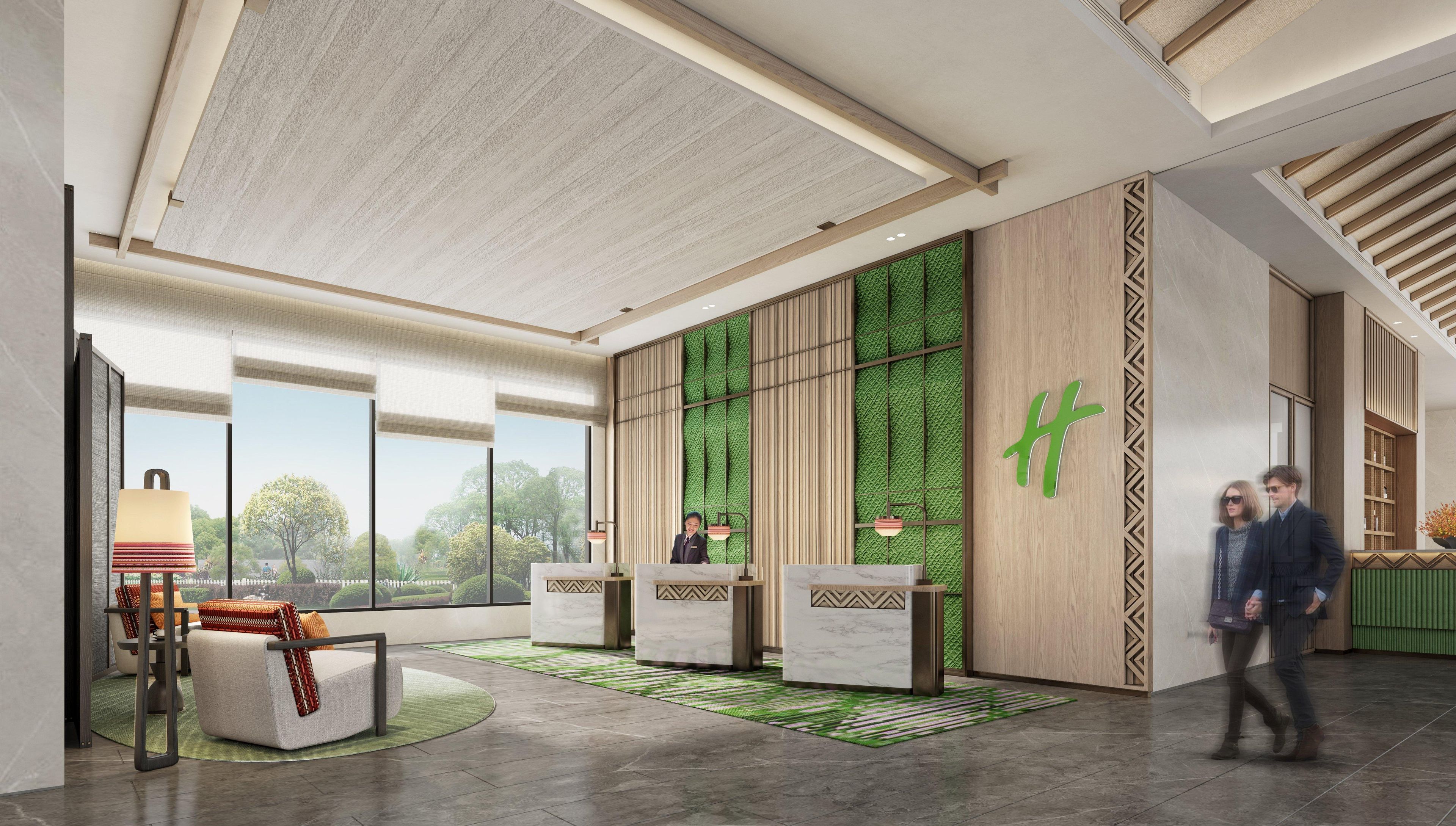 Eine moderne Hotelhalle mit einer Rezeption, einer Sitzecke und großen Fenstern mit Blick ins Freie.