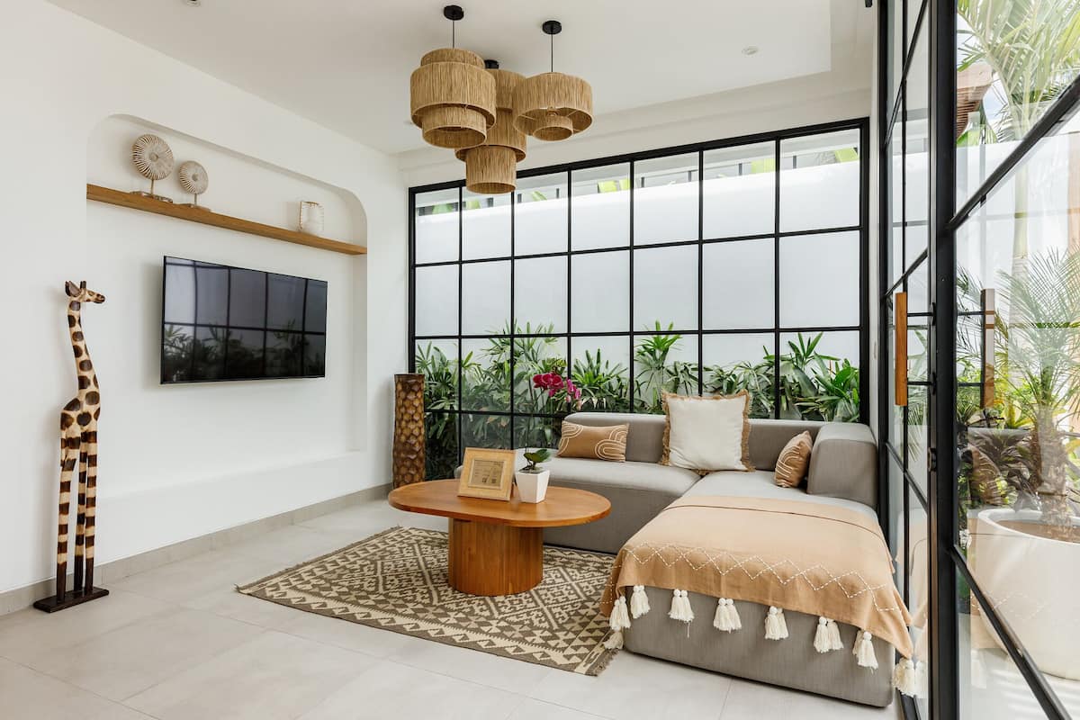 A modern living room with a large window, a sofa, a coffee table, and a giraffe sculpture.