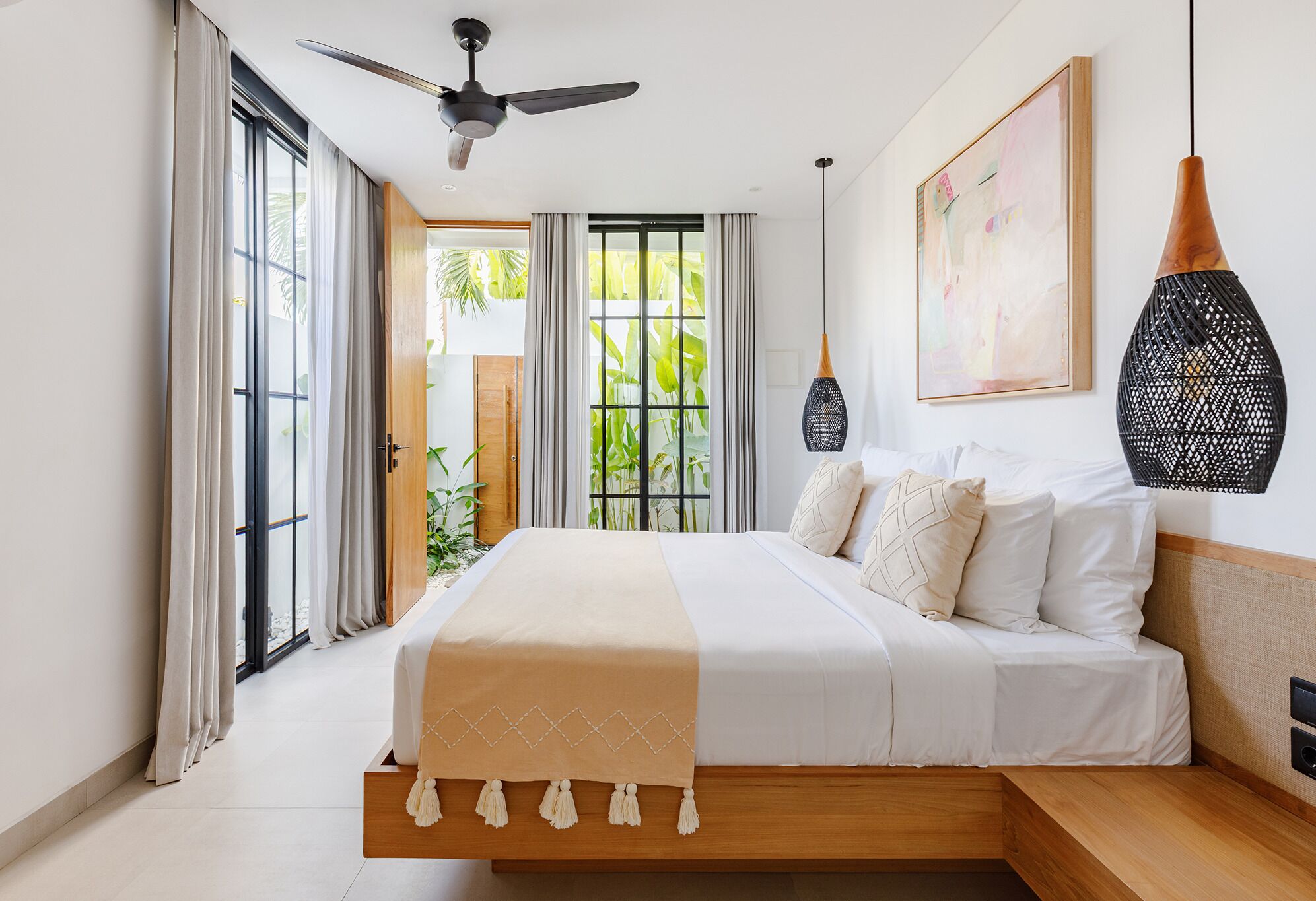 A modern bedroom with a bed, a ceiling fan, a large window with curtains, and a hanging light fixture.