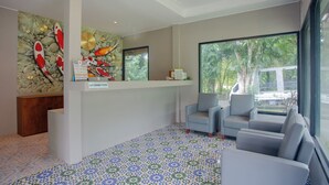 A reception area with a stone wall mural, a reception desk, and seating. - Koh Lanta Amantra Hostel - Women Only (Ko Lanta)