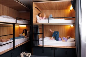 Une chambre de type dortoir, avec des lits superposés, des murs en bois et des armoires intégrées.