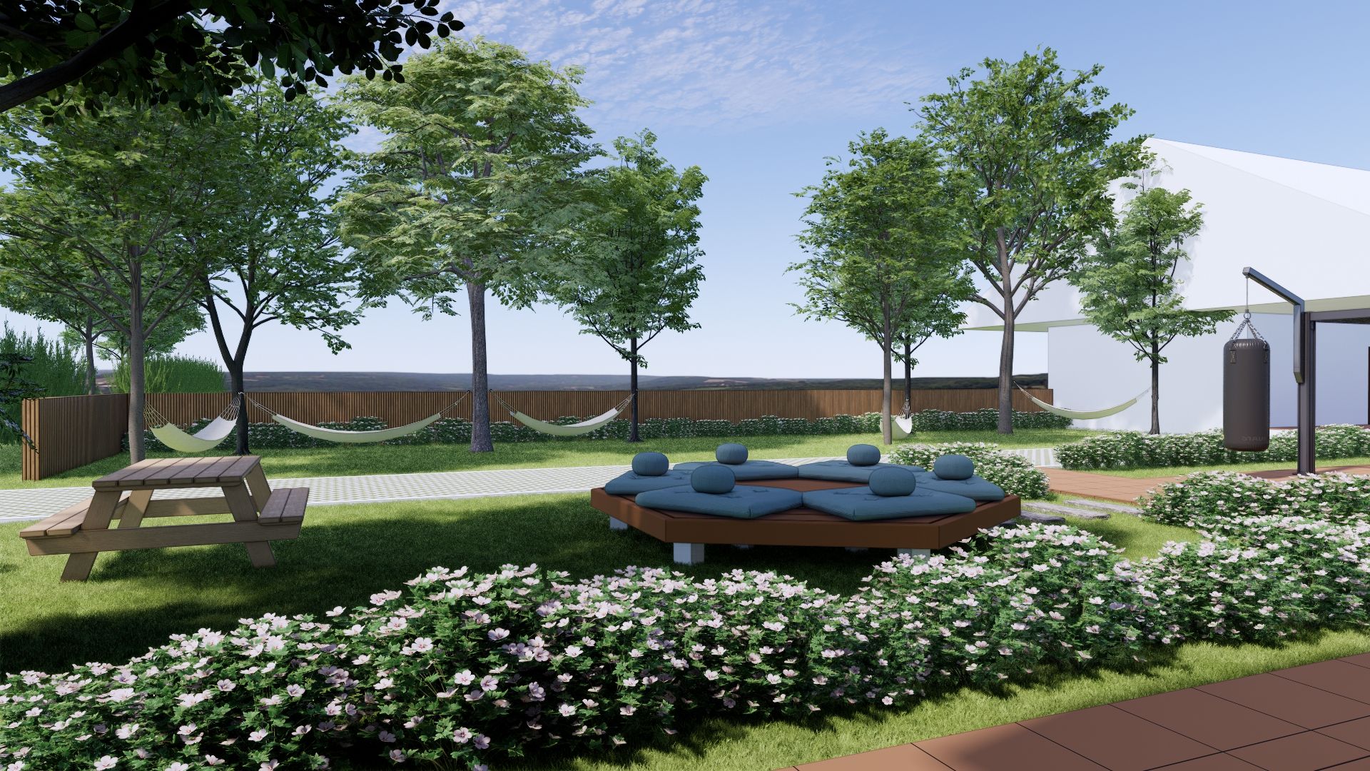 A landscaped outdoor area with a picnic table, seating area with cushions, and flowering bushes.