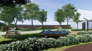 A landscaped outdoor area with a picnic table, seating area with cushions, and flowering bushes. - Koh Lanta Amantra Hostel - Women Only (Ko Lanta)