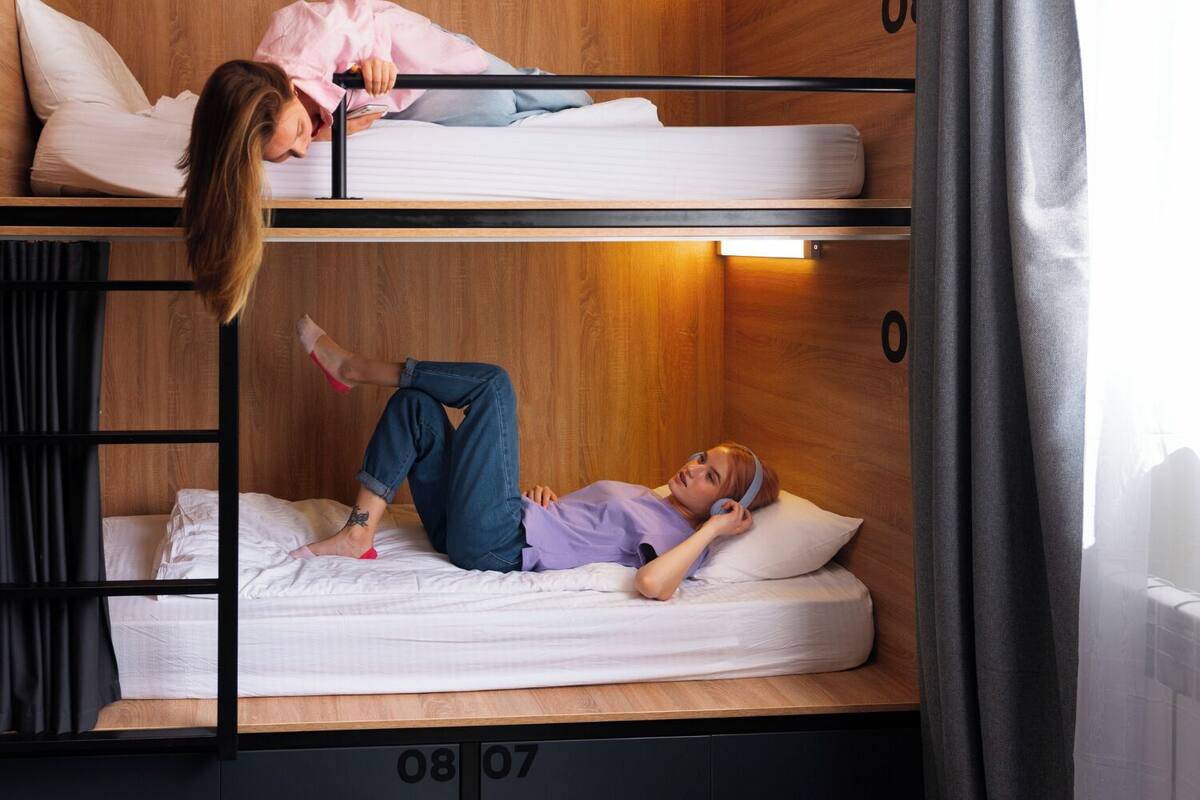 A bunk bed room with two beds, wooden walls, and a window with curtains.
