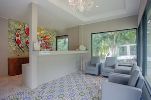 A reception area with a stone wall mural, a reception desk, and seating. - Koh Lanta Amantra Hostel - Women Only (Ko Lanta)