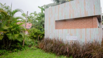A building with a 'Only Car Parking' sign, surrounded by greenery and palm trees.