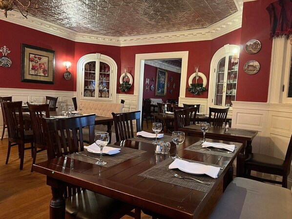 A dining area with multiple tables and chairs, a chandelier, and decorative wall elements.