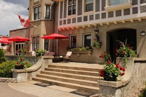 A building with a stone facade, red flower planters, and a flag. - The Trinity Resort - Scenery (Pembroke)