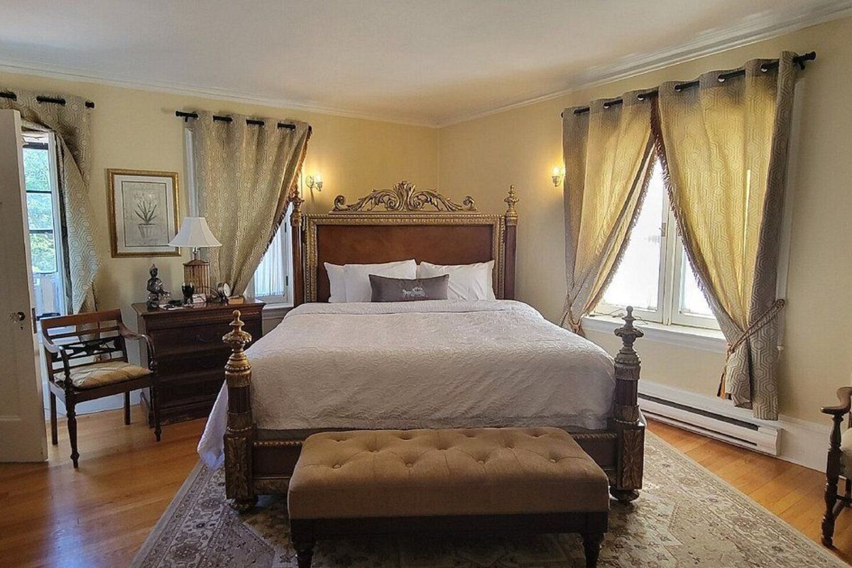 A bedroom with a large bed, a nightstand, a chair, and a dresser.