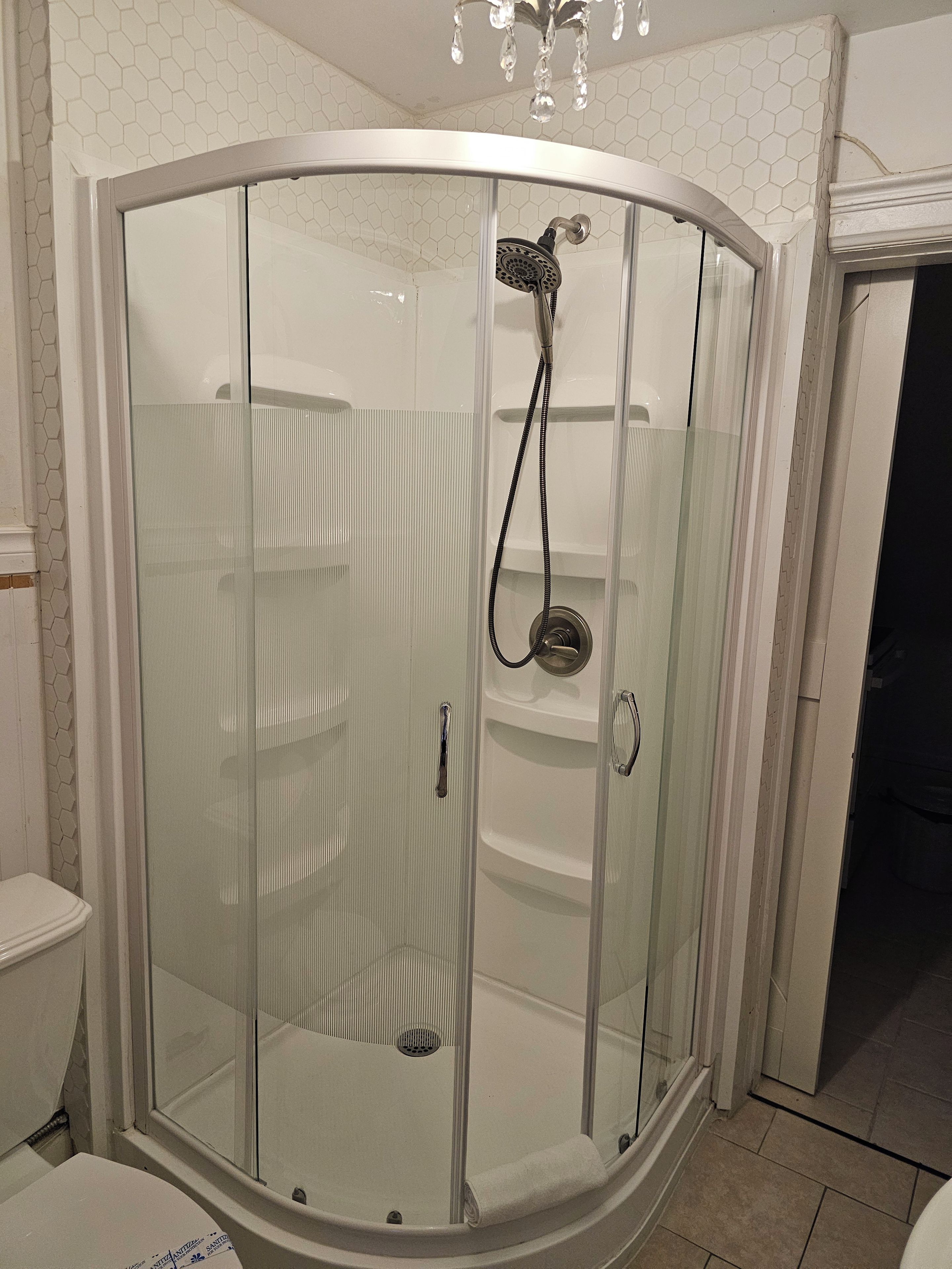 A glass-enclosed shower stall with a handrail and a showerhead.