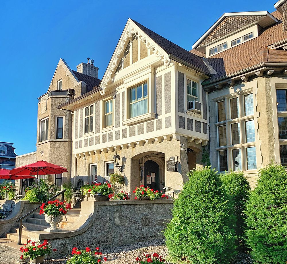 A large, two-story building with a prominent entrance, multiple windows, and a stone facade.