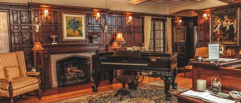 Una sala espaciosa con un piano, una chimenea y un tapete grande.