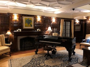 A grand room with a piano, wooden paneling, a fireplace, and a large rug. - The Trinity Resort - Scenery (Pembroke)