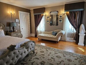 A bedroom with a large bed, a nightstand, a dresser, a chaise lounge, and a mirror. - The Trinity Resort - Scenery (Pembroke)