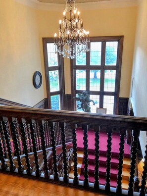 A grand staircase with a chandelier, a clock, and a view of the outdoors through large windows. - The Trinity Resort - Scenery (Pembroke)