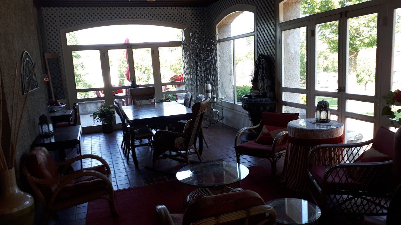 A sunlit patio with a dining table, chairs, and a small round table with a lamp.