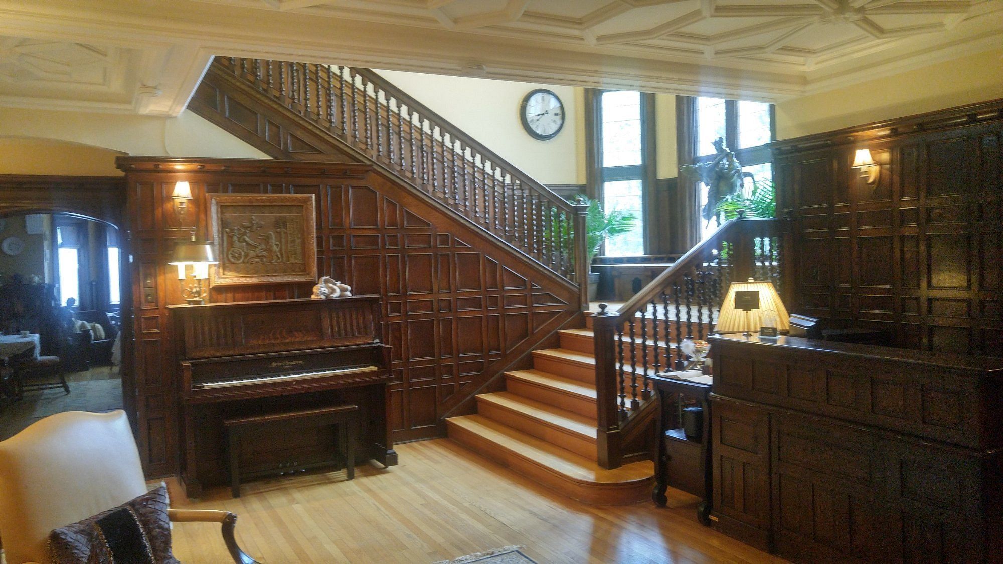 A grand staircase with wooden railings and a piano in the foreground.