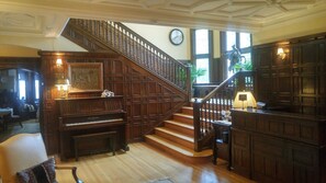 Una imponente escalera con barandillas de madera y un piano al frente.
