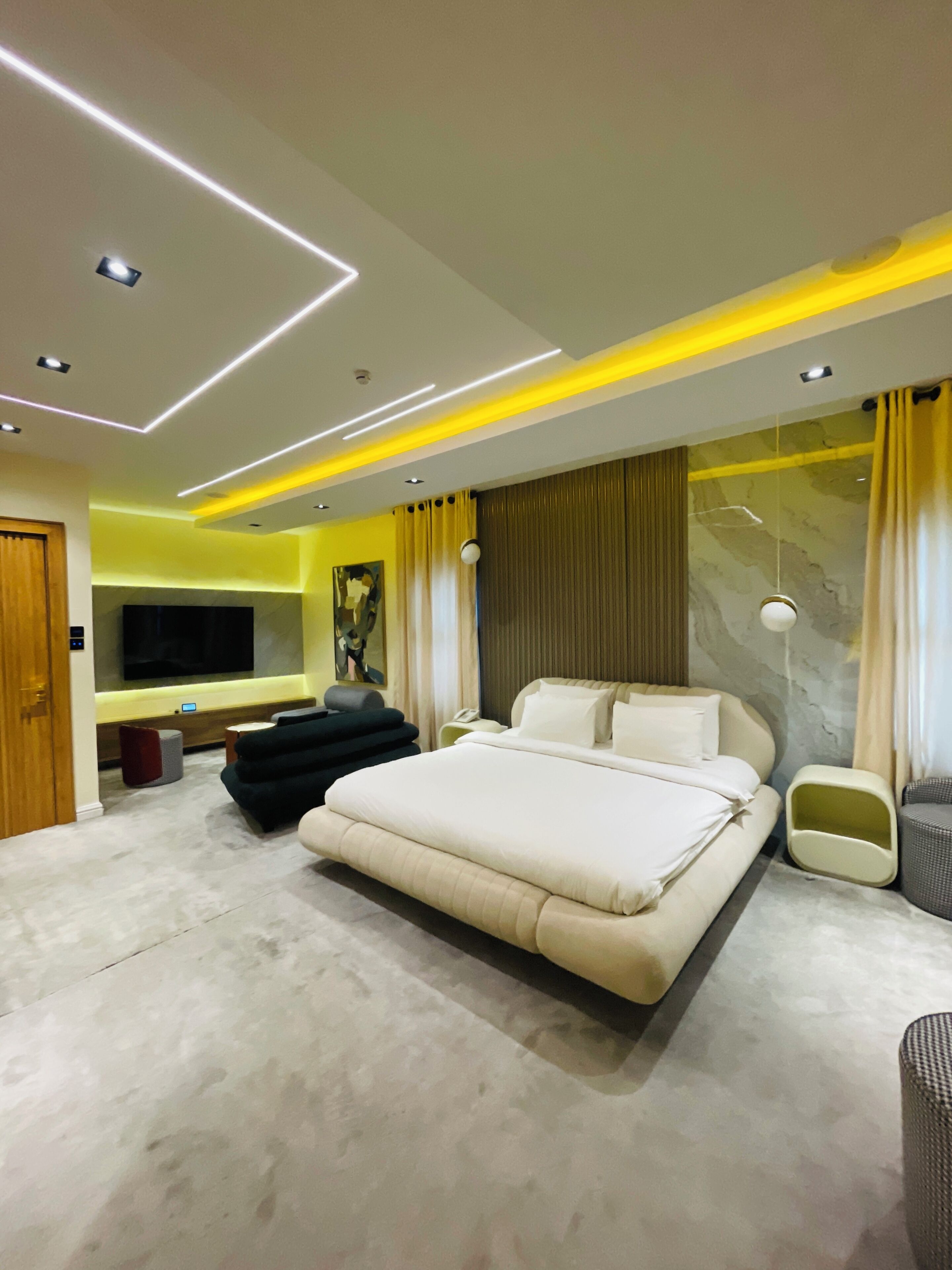 Une chambre moderne dotée d’un grand lit, d’un téléviseur à écran plat et d’un éclairage d’ambiance.