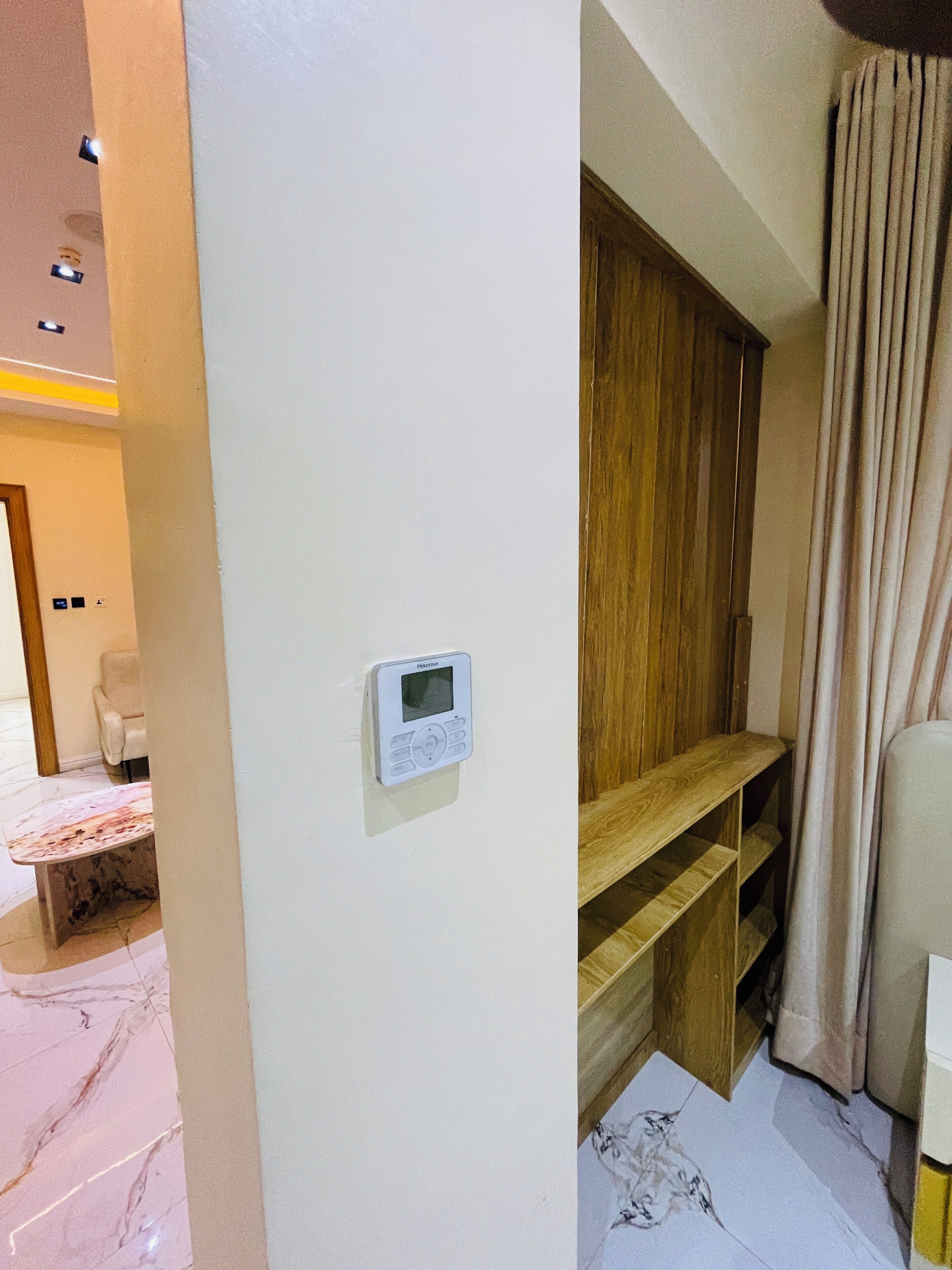 A modern room with a built-in heater, wooden shelving, a seating area, and a curtain.