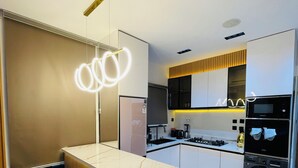 A modern kitchen with a marble countertop, built-in appliances, and a unique light fixture. - The GlobalNomad Enterprise (Lekki)