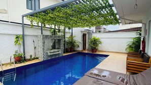A swimming pool with a wooden deck, a covered seating area, and potted plants. - The GlobalNomad Enterprise (Lekki)