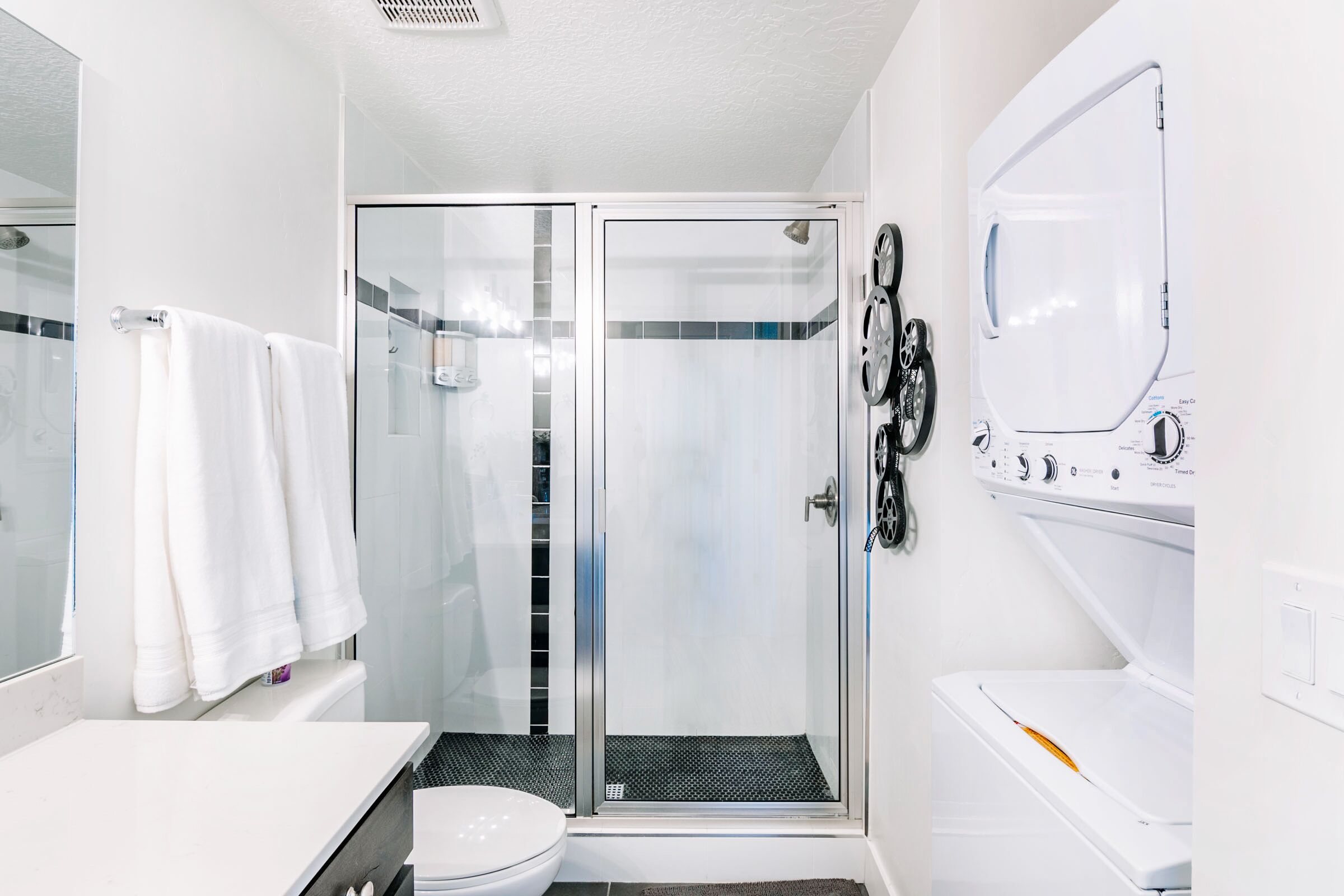 Un baño moderno con cabina de ducha de vidrio, inodoro y lavadora integrada.