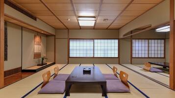 Una habitación japonesa tradicional con suelo de tatami, una mesa baja y puertas correderas.