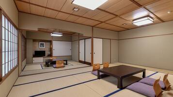 A tatami mat room with a low table, chairs, a television, and sliding doors.