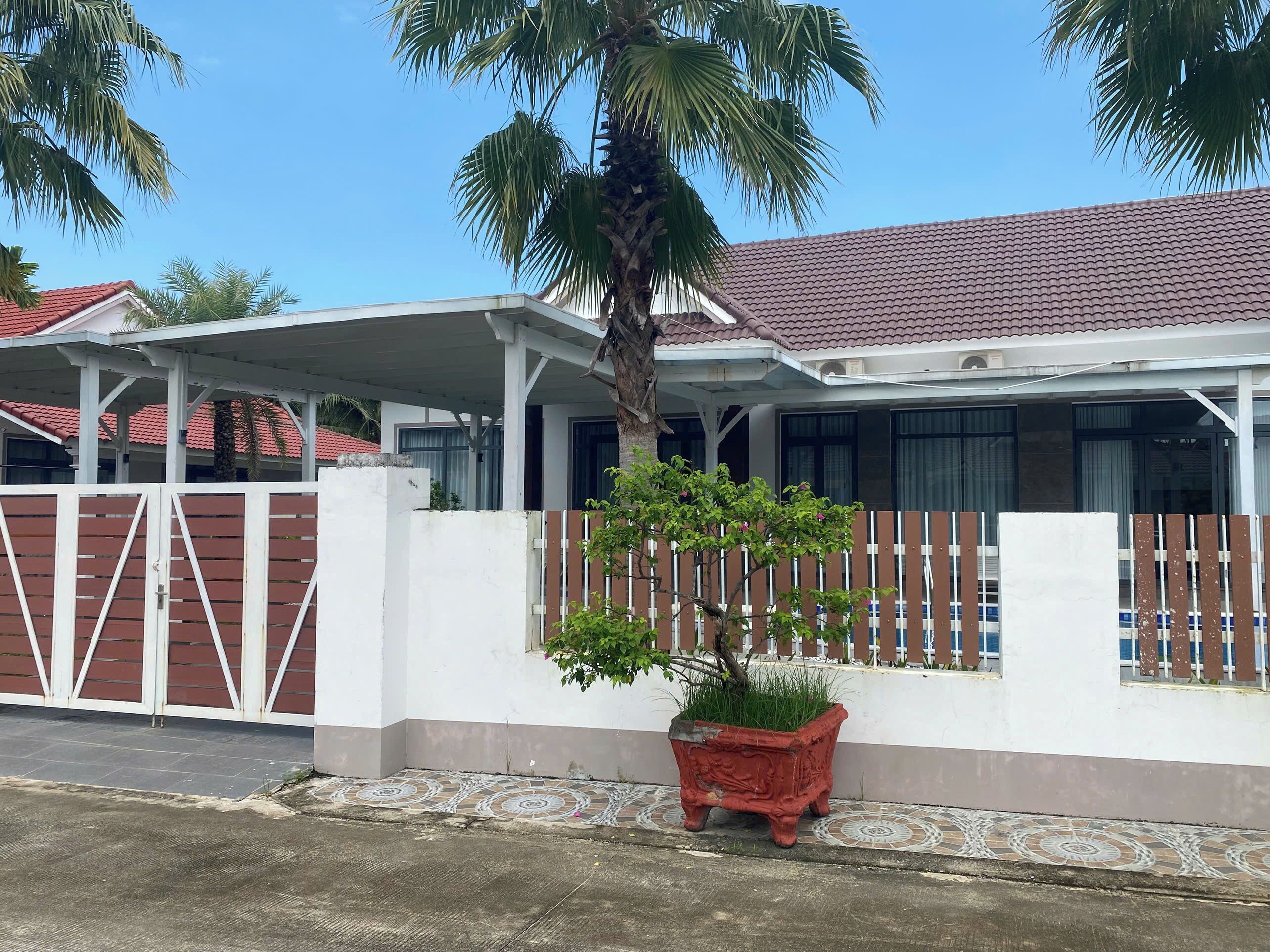 A residential building with a red-tiled roof, white walls, and a gated entrance.